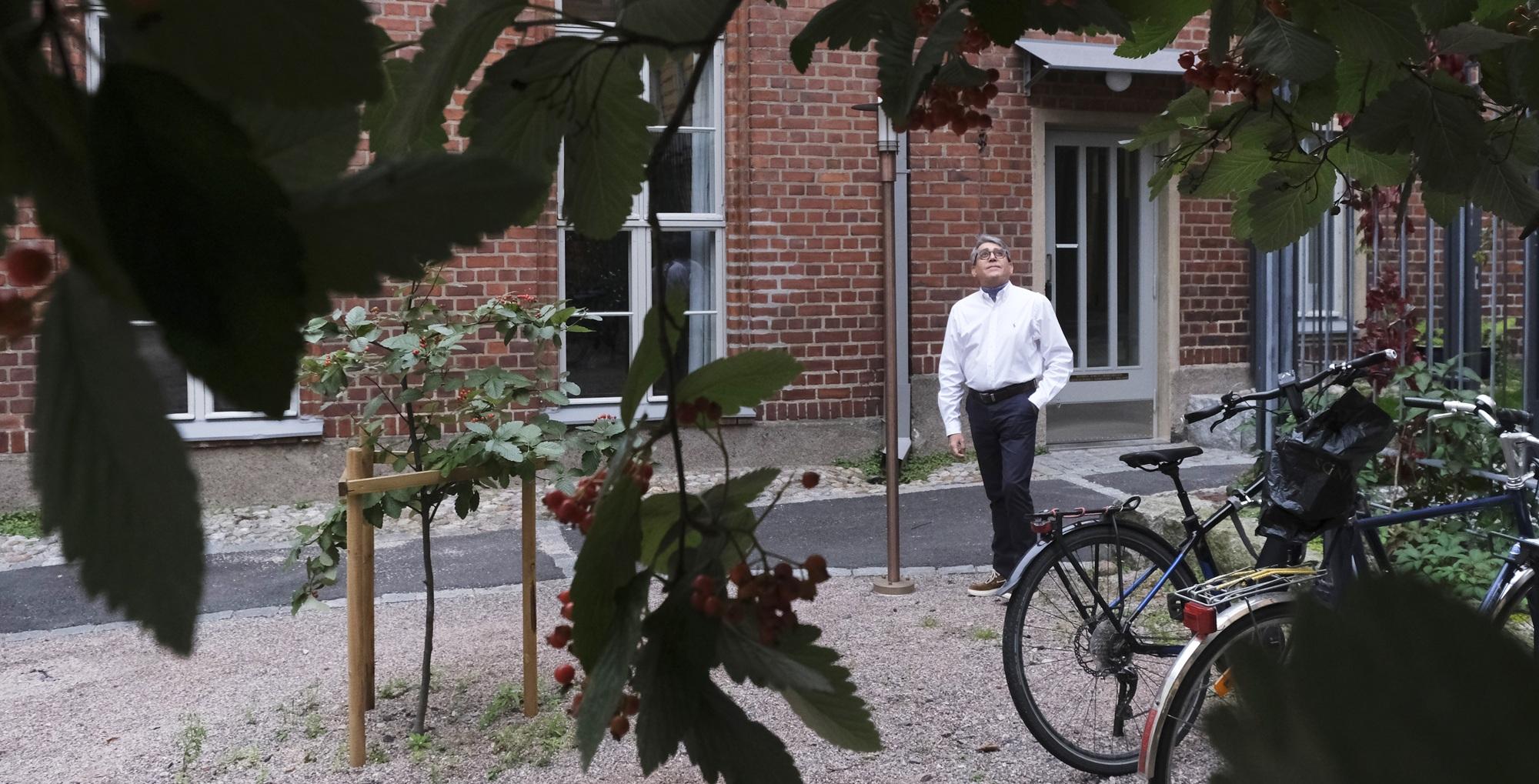 Miesoletettu seisoo pihalla, taustalla punatiilinen rakennus.