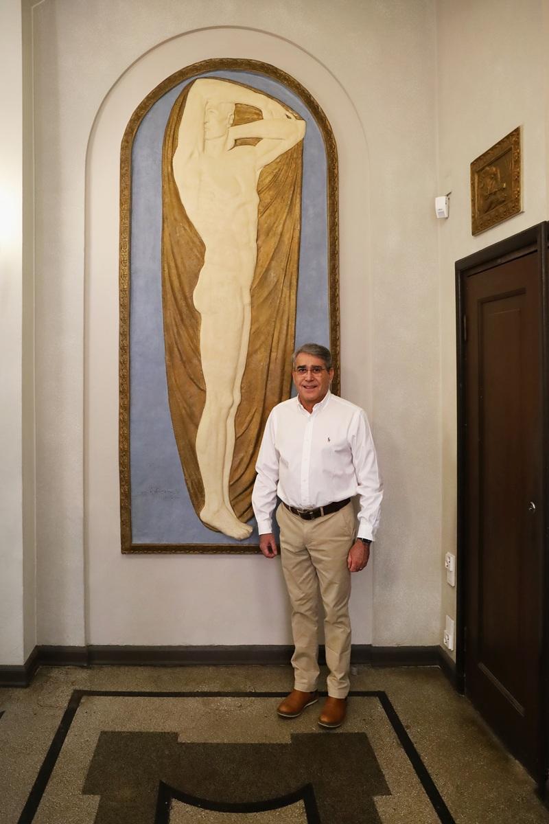 Miesoletettu henkilö poseeraa ison reliefin vieressä.