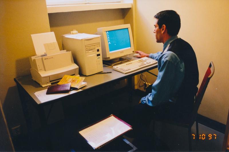 Miesoletettu henkilö vanhanaikaisen pöytätietokoneen äärellä.