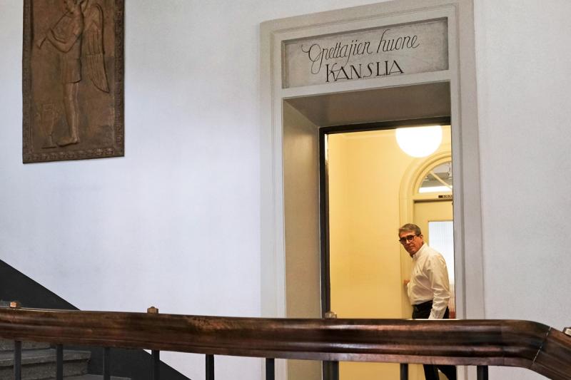 Miesoletettu henkilö oviaukossa, jonka yllä lukee Opettajien huone.