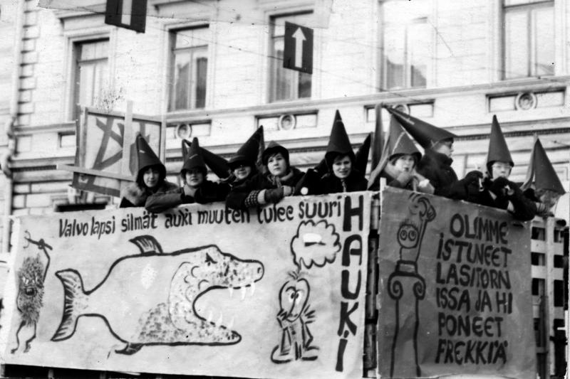 Vanha kuva penkkarirekka-ajelusta, kyydissä olevilla mustat suipot hatut päässään.