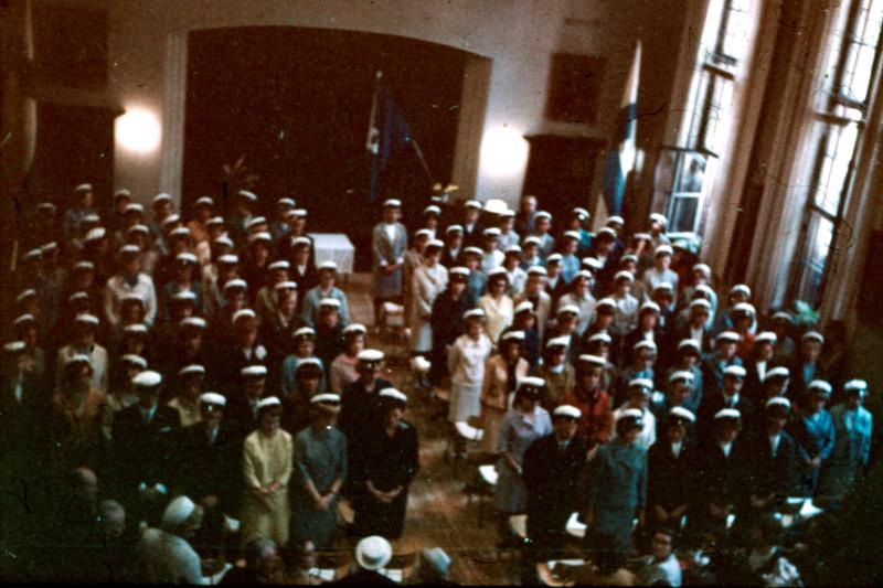 Salissa ylioppilaslakit päässään seisovia ihmisiä.